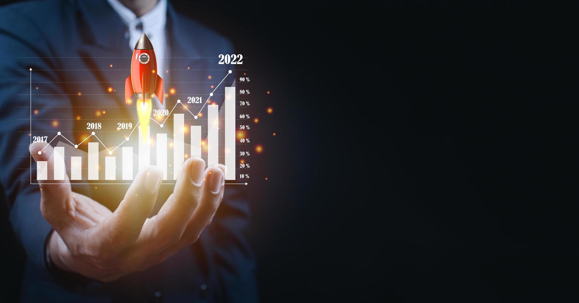 Businessman holding and showing a growing virtual hologram of statistics, graph and chart with arrow up on dark background. photo