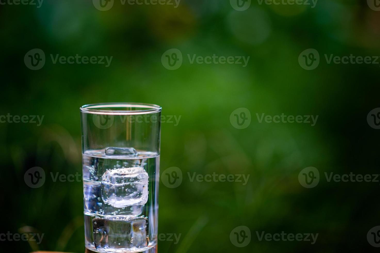 A glass of clean water with ice placed on the table ready to drink photo