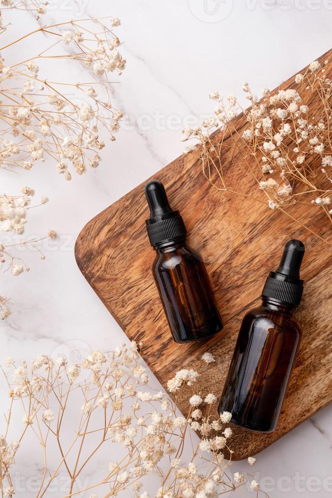 amber glass essential oil dropper bottle with pipette on concrete background with white flowers photo