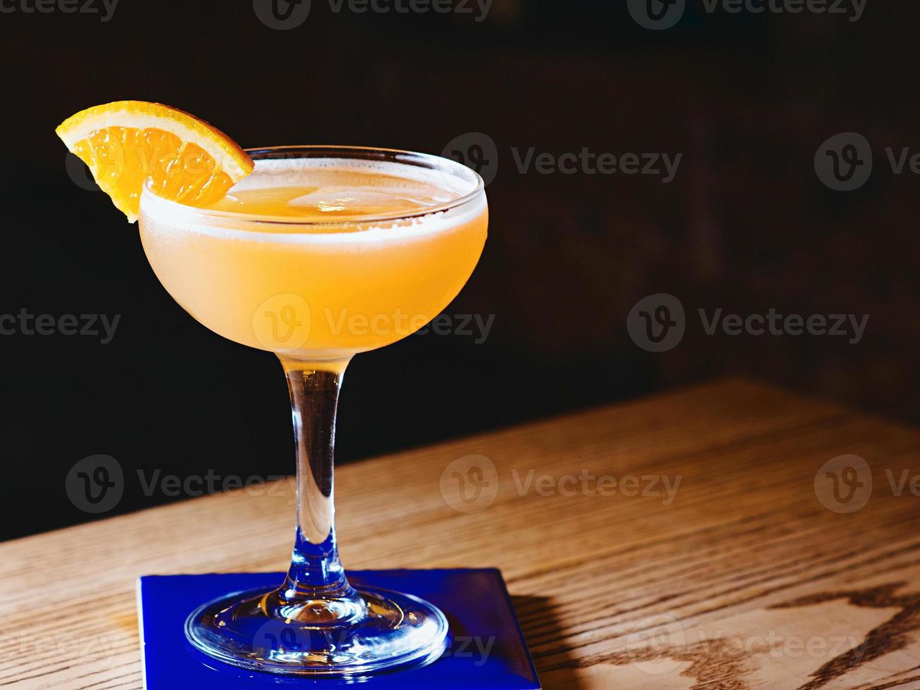 cóctel agrio de alcohol naranja con cítricos en un elegante vaso en el bar foto