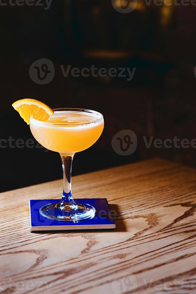 orange alcohol sour cocktail with citrus in elegant glass in the bar photo