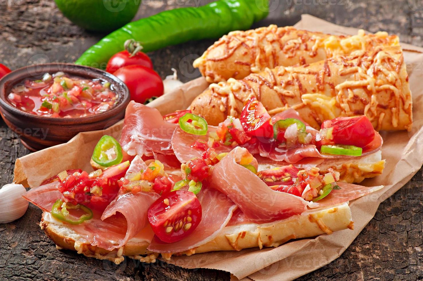 Salsa dip in bowl of bread and cheese sticks on wooden background photo