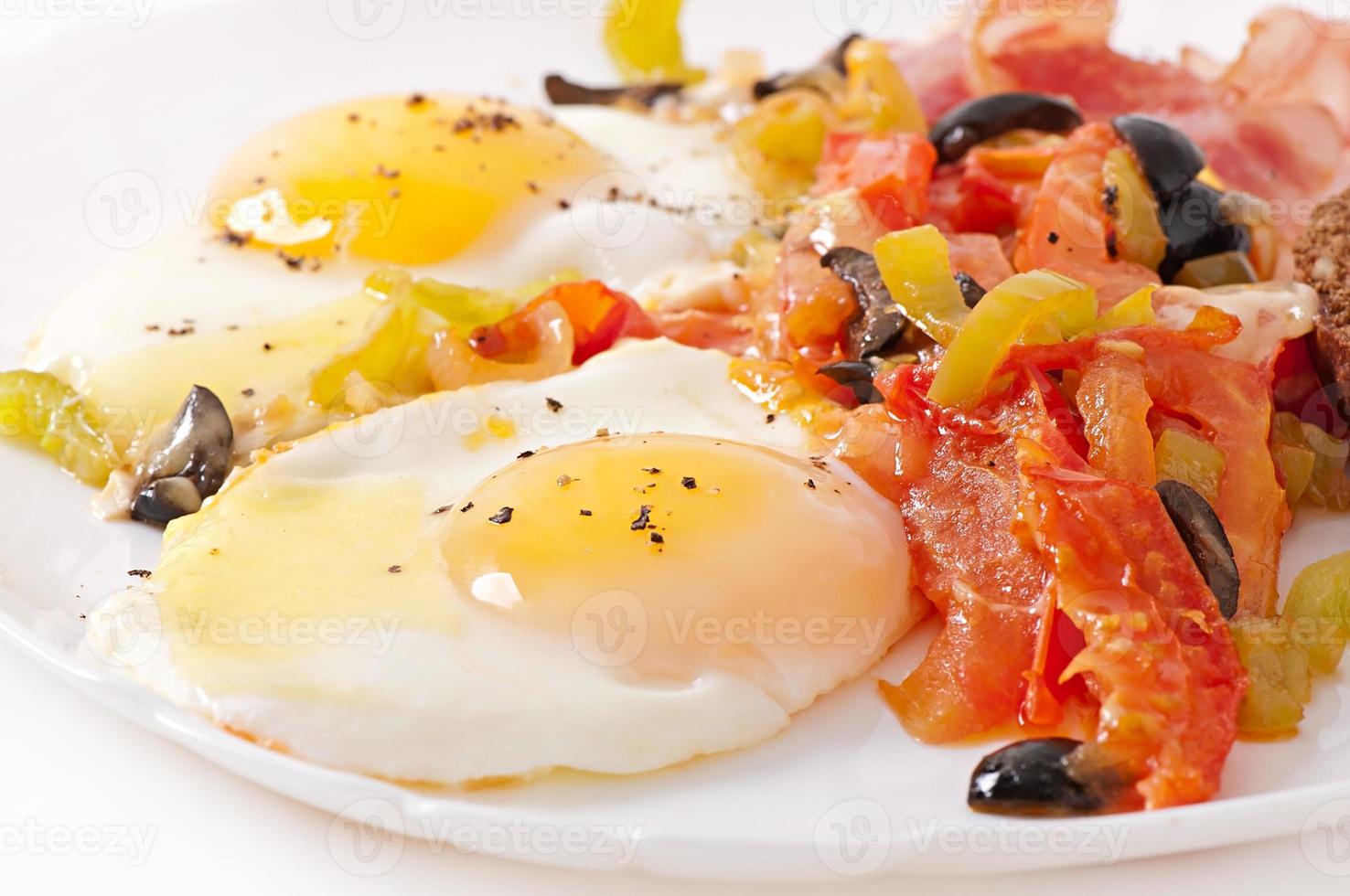 Breakfast - fried eggs with bacon, tomatoes, olives and slices of cheese photo