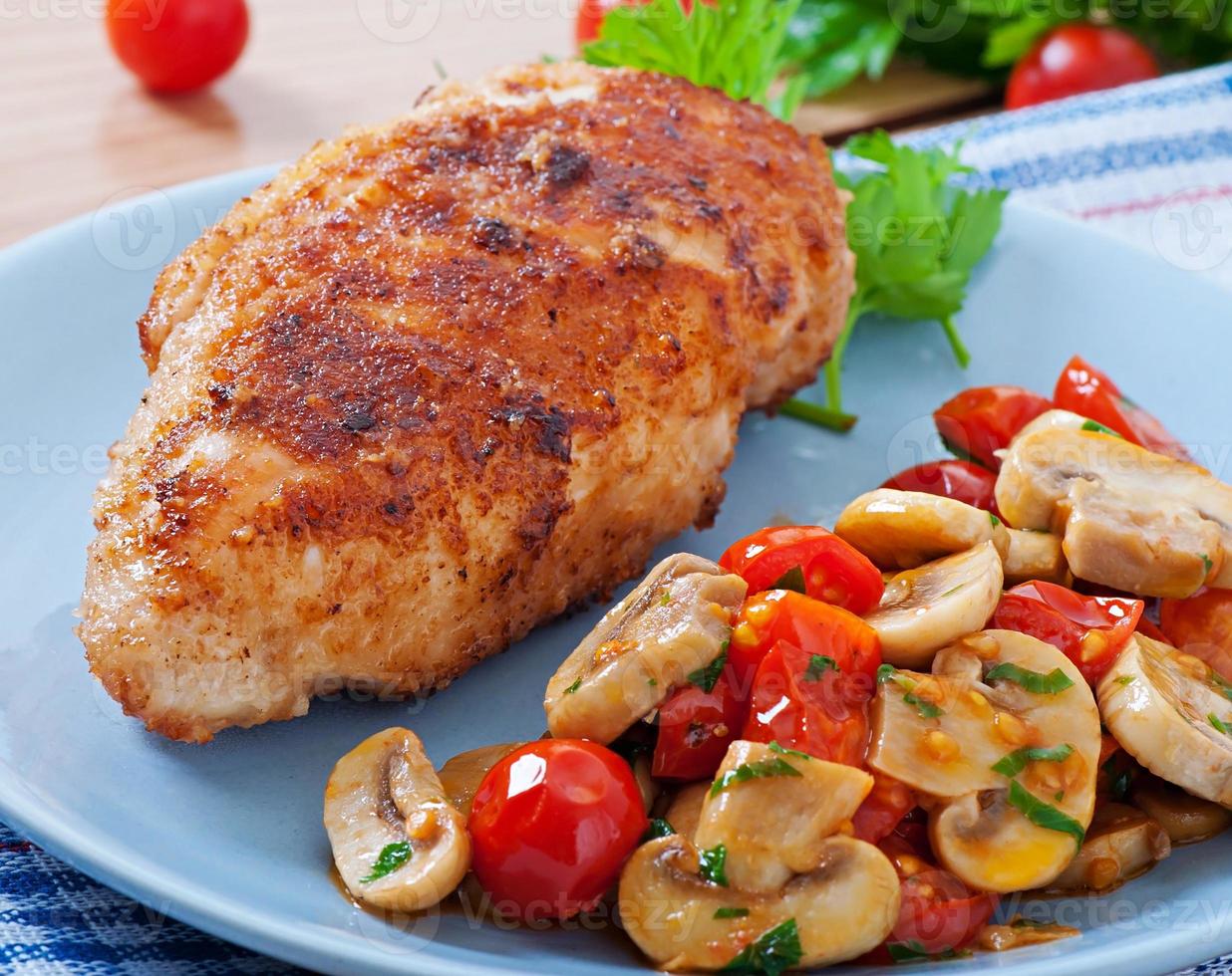 Chicken fillet in crispy breadcrumbs garnished with mushrooms and tomatoes photo