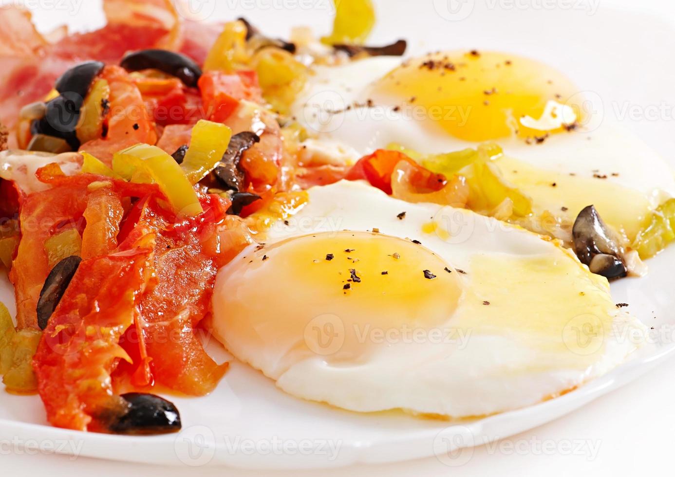 Breakfast - fried eggs with bacon, tomatoes, olives and slices of cheese photo