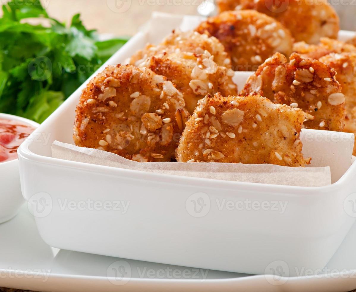 Chicken nuggets coated in cereals, crumbs and sesame photo