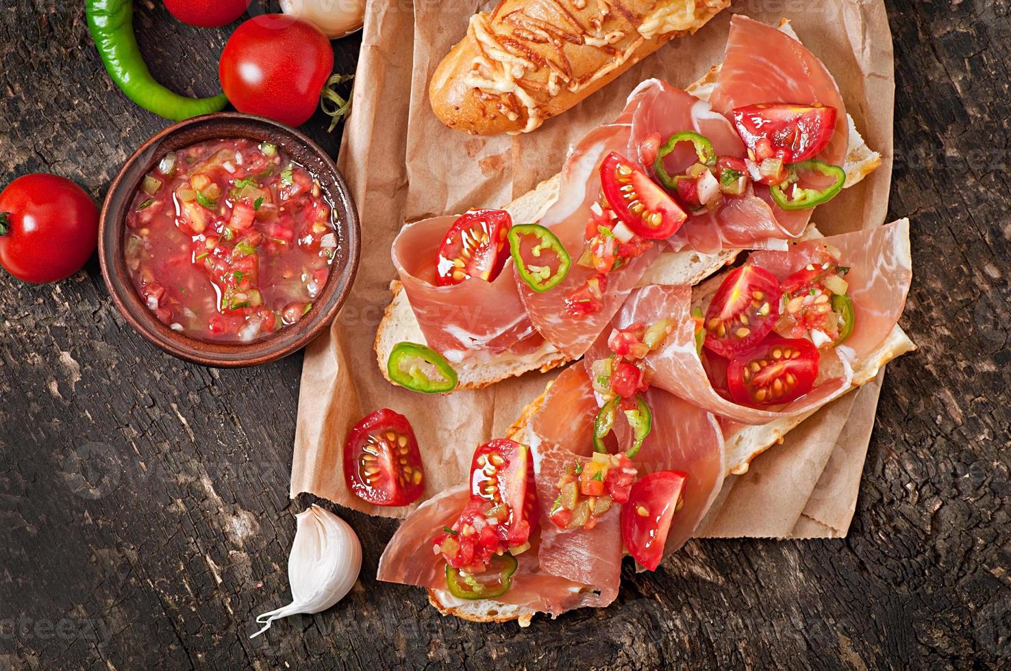 Salsa dip in bowl of bread and cheese sticks on wooden background photo