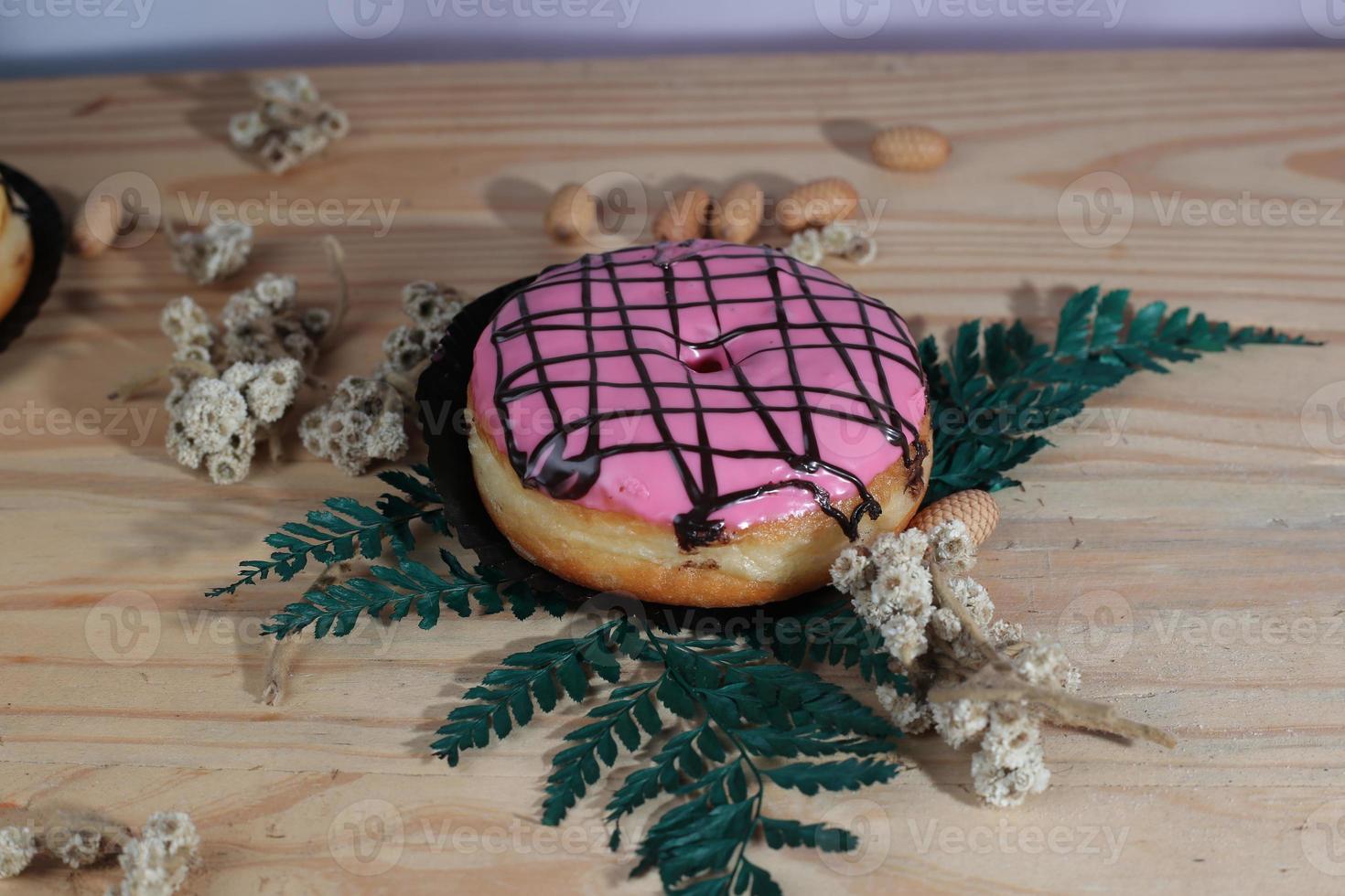 Brown donuts with sprinkles isolated on a wooden background photo