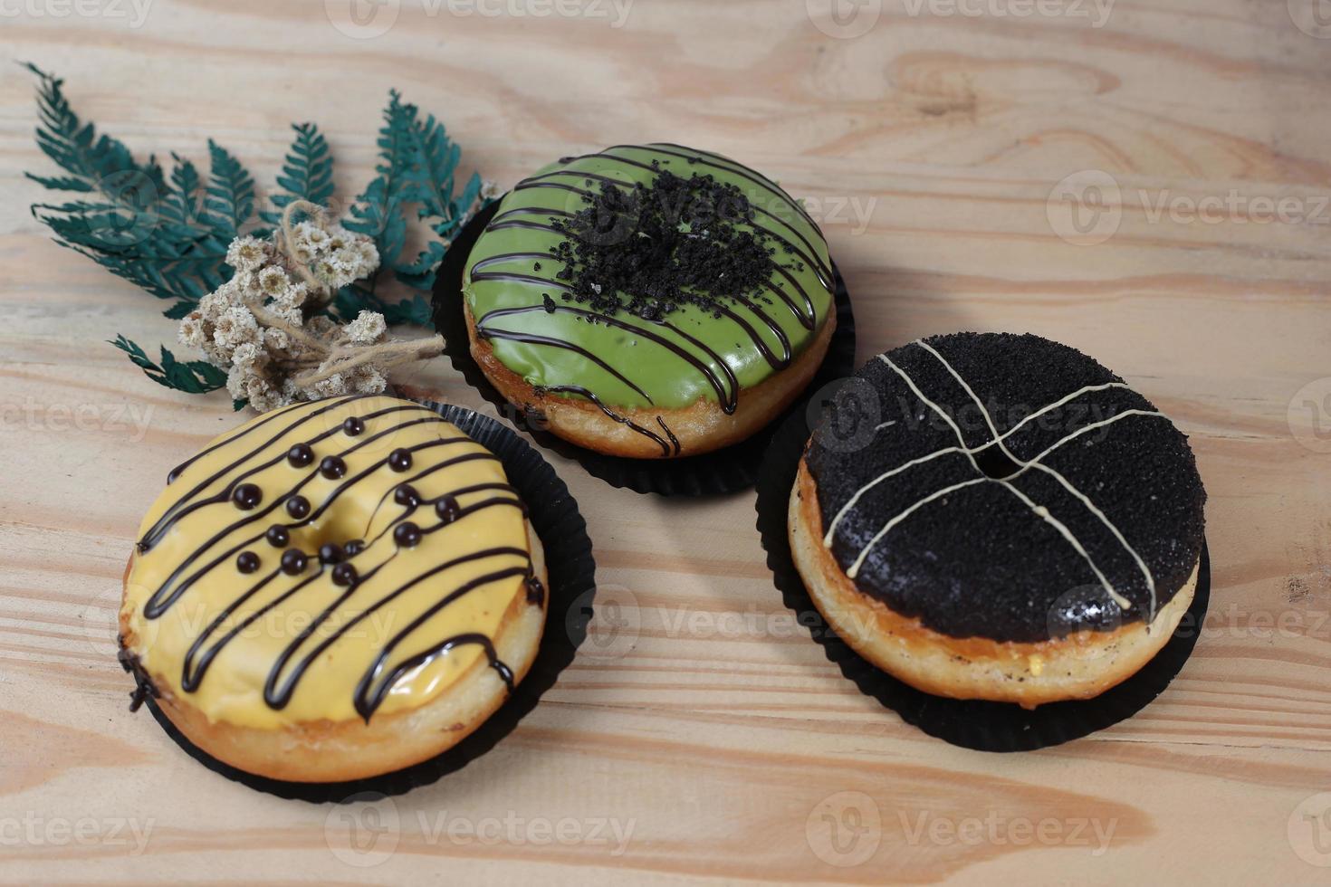 Brown donuts with sprinkles isolated on a wooden background photo