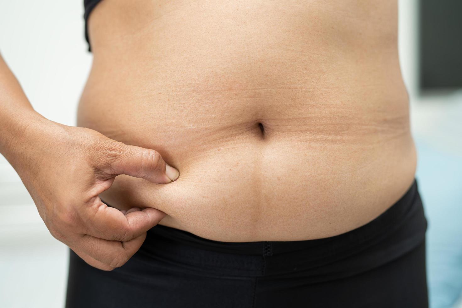 mujer asiática con sobrepeso muestra el vientre gordo en la oficina. foto