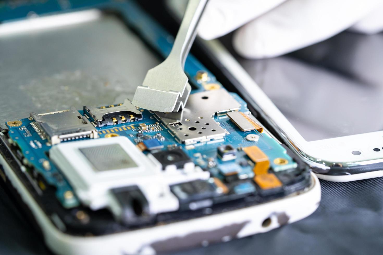 Technician repairing inside of smartphone, Integrated Circuit. the concept of data, hardware, technology. photo