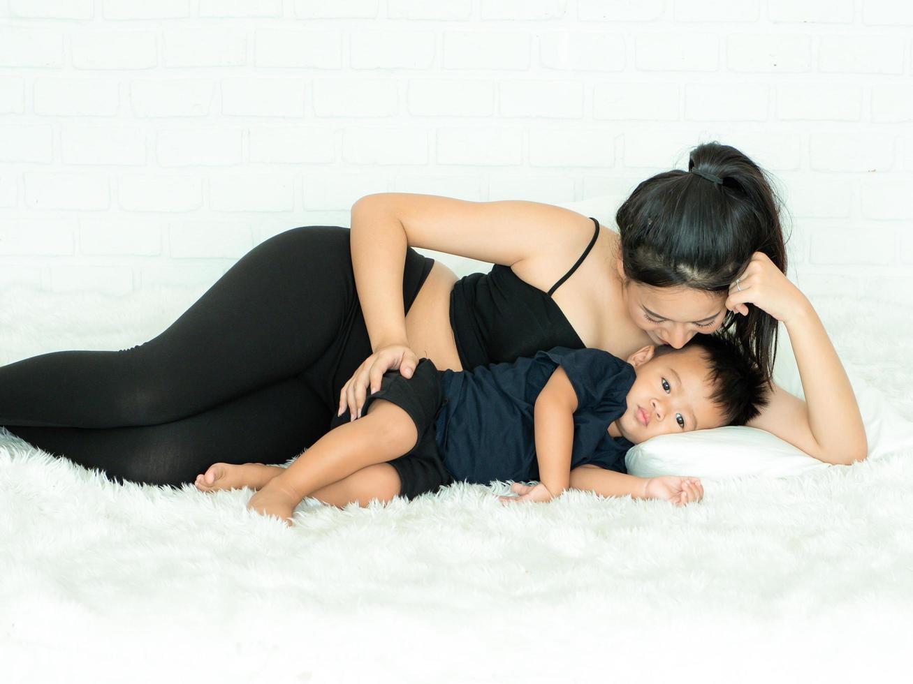 A beautiful pregnant woman lying in bed and caring for her son happily photo