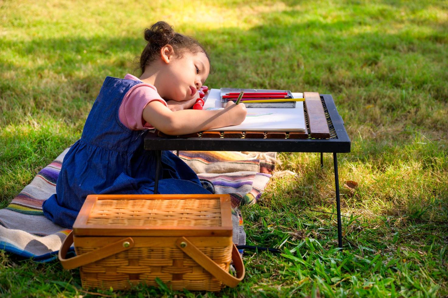 una niña pequeña está sentada en la tela y pintada en el papel colocado sobre una mesa foto