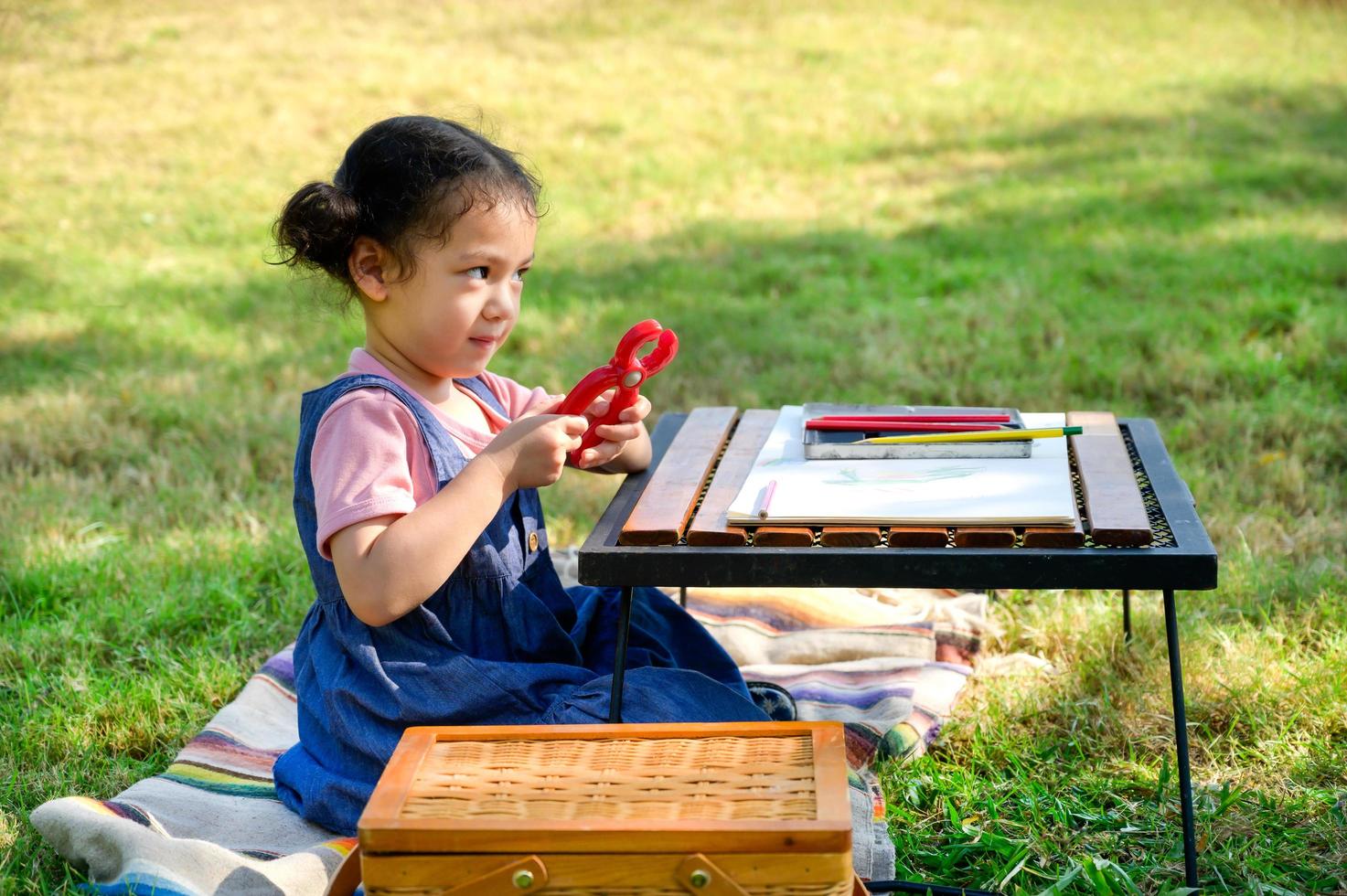 una niña pequeña está sentada en la tela y jugando un juguete antes de pintar en el papel foto