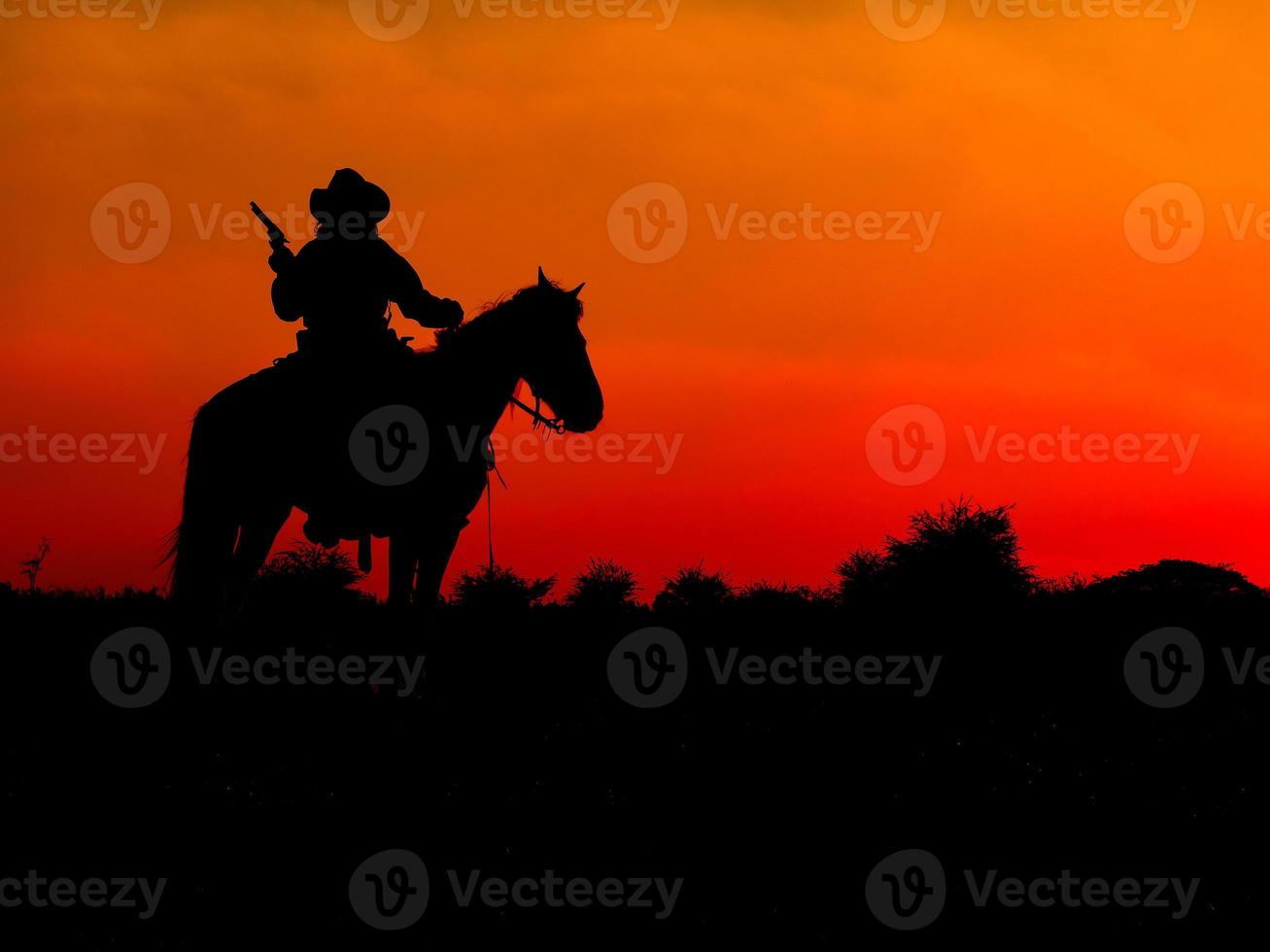 Western cowboys are sitting on horseback under the sun and preparing to use guns to protect themselves in a land that is not yet legal photo