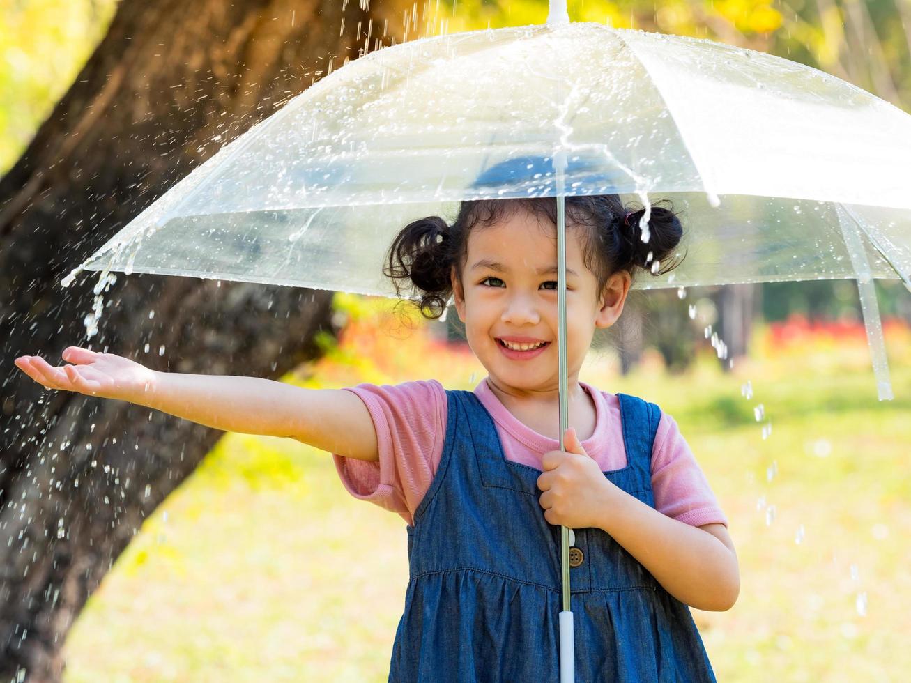 A little girl was happily standing in an umbrella against the rain photo