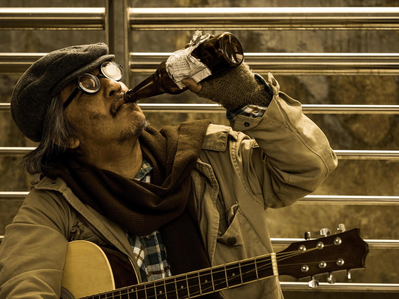 A poor homeless man drink alcohol befor play music for donations photo