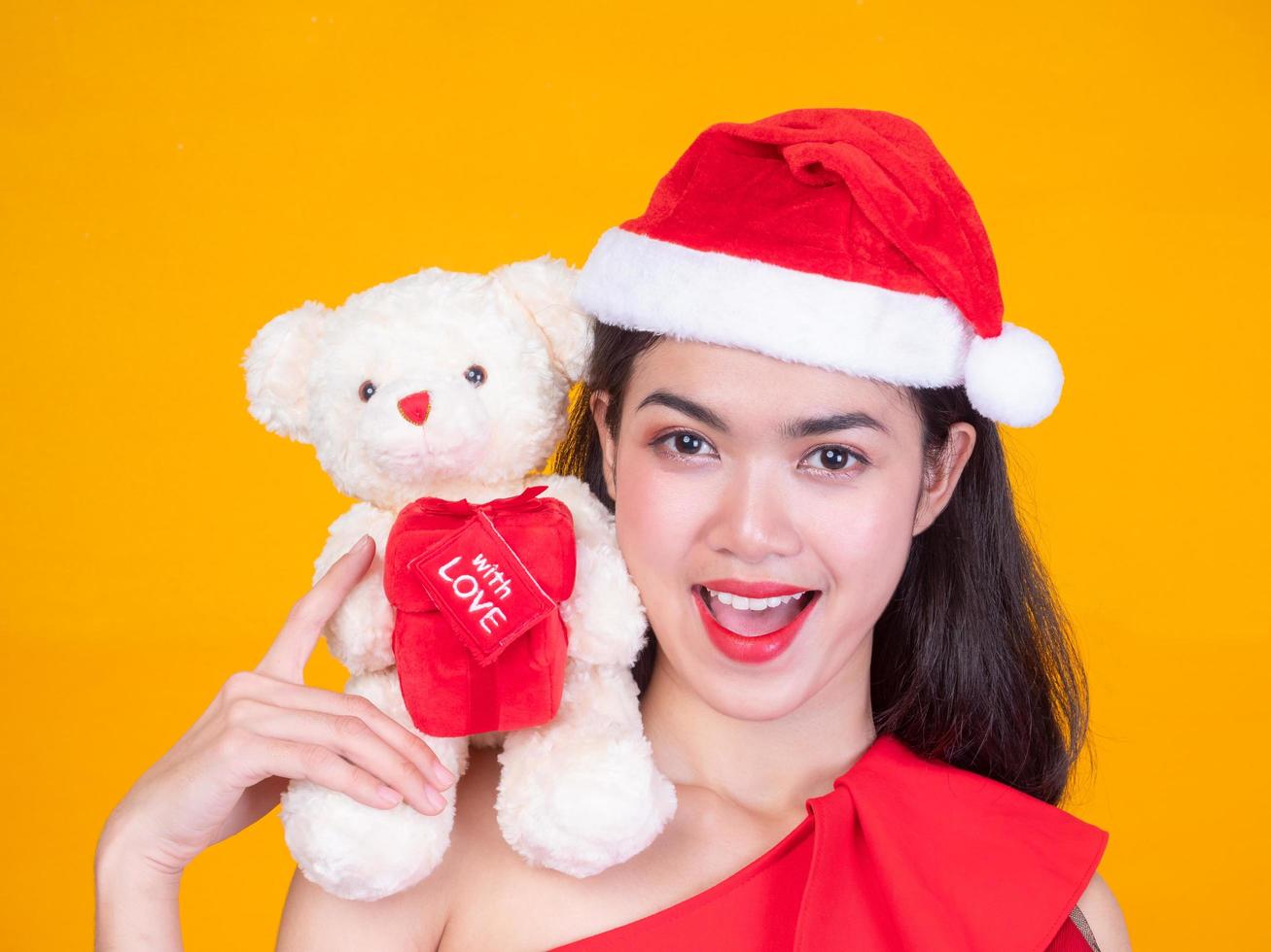 hermosa chica asiática con traje rojo de santa y oso de amor en el día de la celebración foto