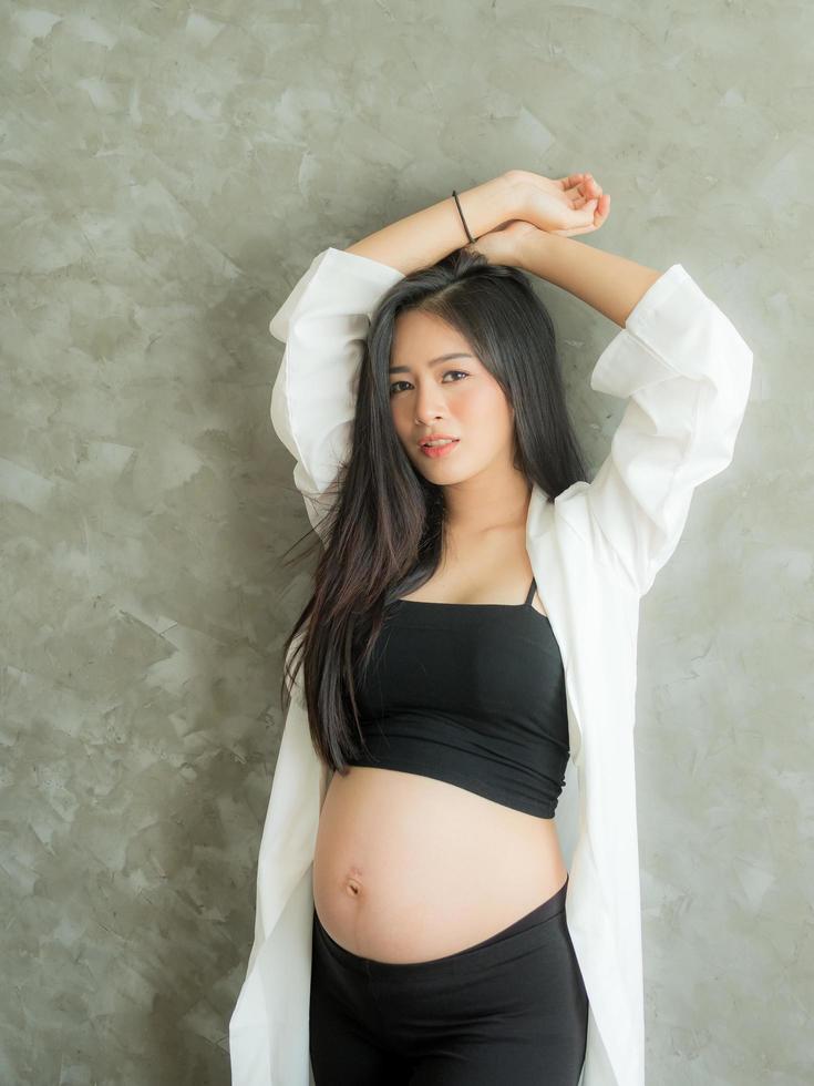 A beautiful pregnant woman stands in the room and poses as a model with a beautiful pose photo