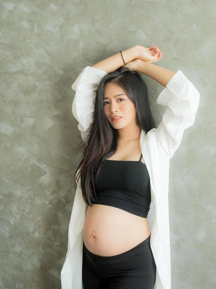 una hermosa mujer embarazada se para en la habitación y posa como modelo con una hermosa pose foto