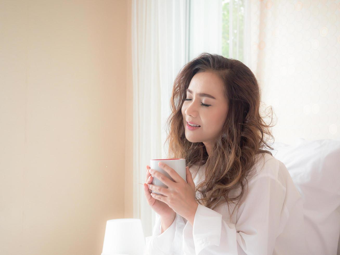 Beautiful woman is drinking coffee on the bed photo