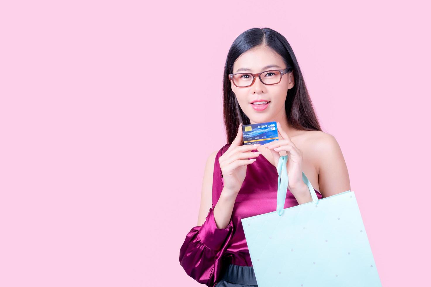 una hermosa mujer asiática está feliz y piensa que gastará muchas de sus tarjetas de crédito foto