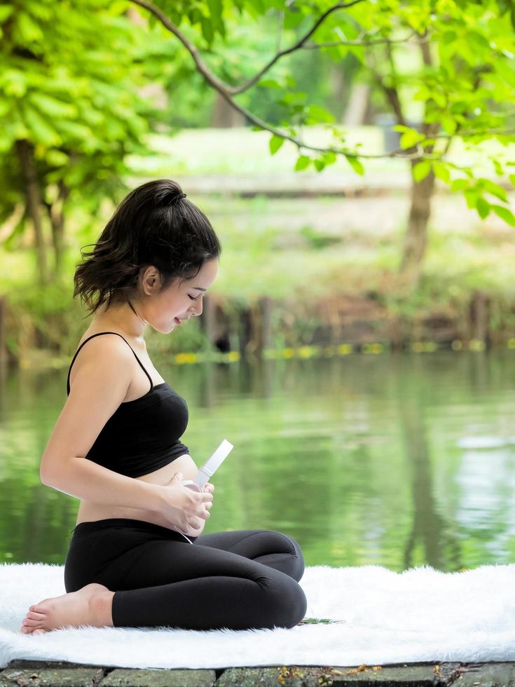 hermosas mujeres embarazadas se sientan en el parque, dejan que los niños en el vientre escuchen música foto