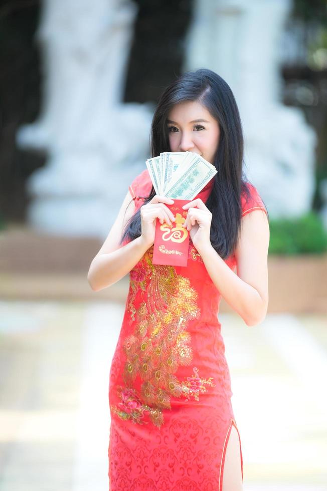 Asian woman in Chinese national costumes hold a money for the Chinese New Year event photo