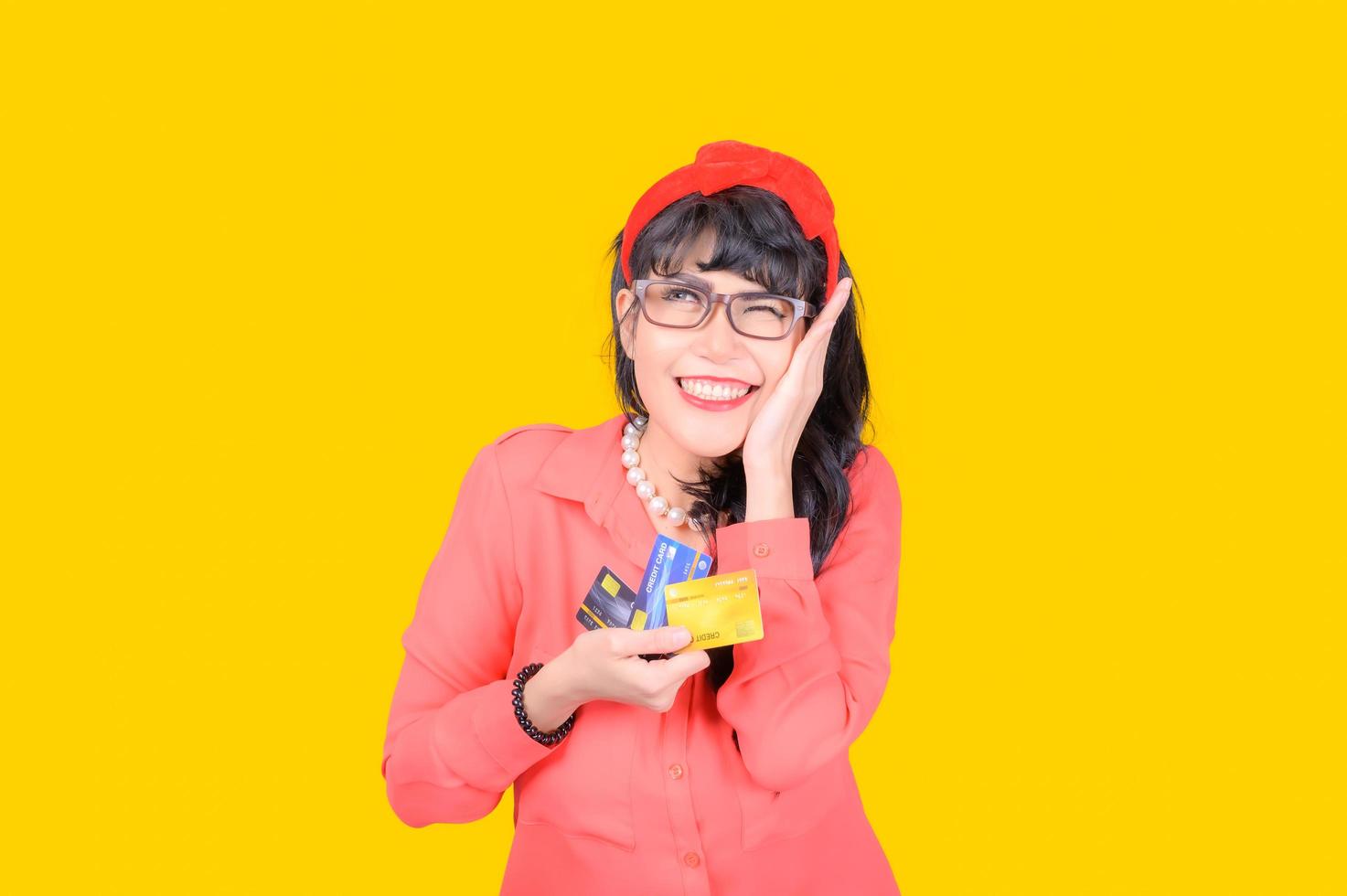 A beautiful Asian woman is happy and thinks that she will spend with many of her credit cards photo