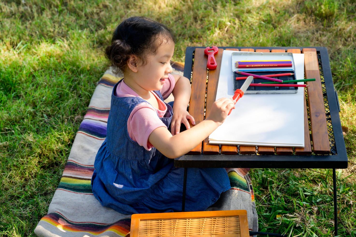 A little girl is sitting on the cloth and playing a toy befor painted on the paper photo