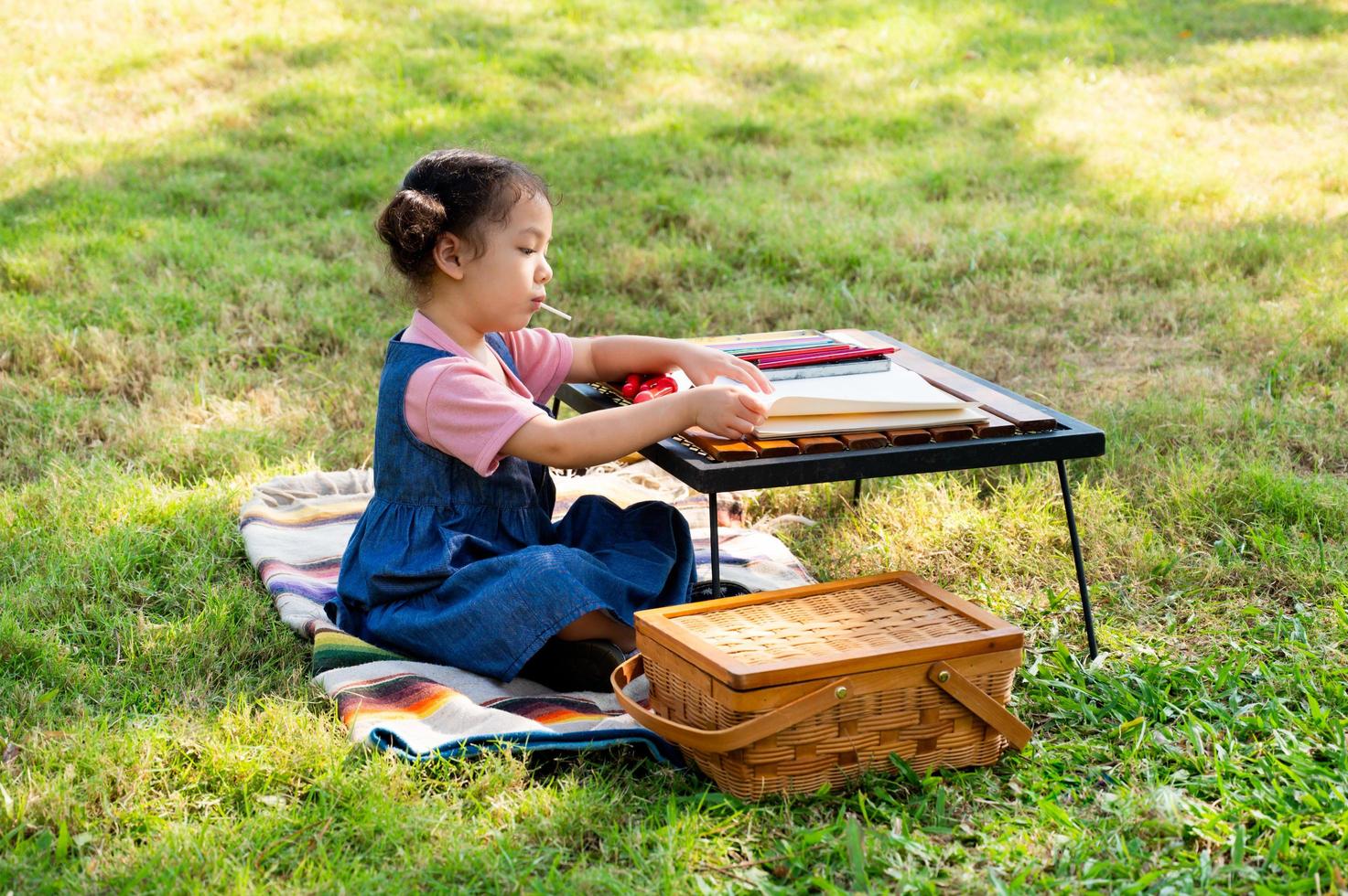 A little girl is sitting on the cloth and painted on the paper placed on a table photo