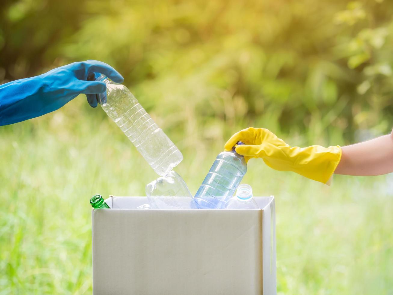 mujeres voluntarias recogen botellas de agua de plástico en el área del parque, de personas que se niegan a tirar la basura en una caja de papel para reciclar foto