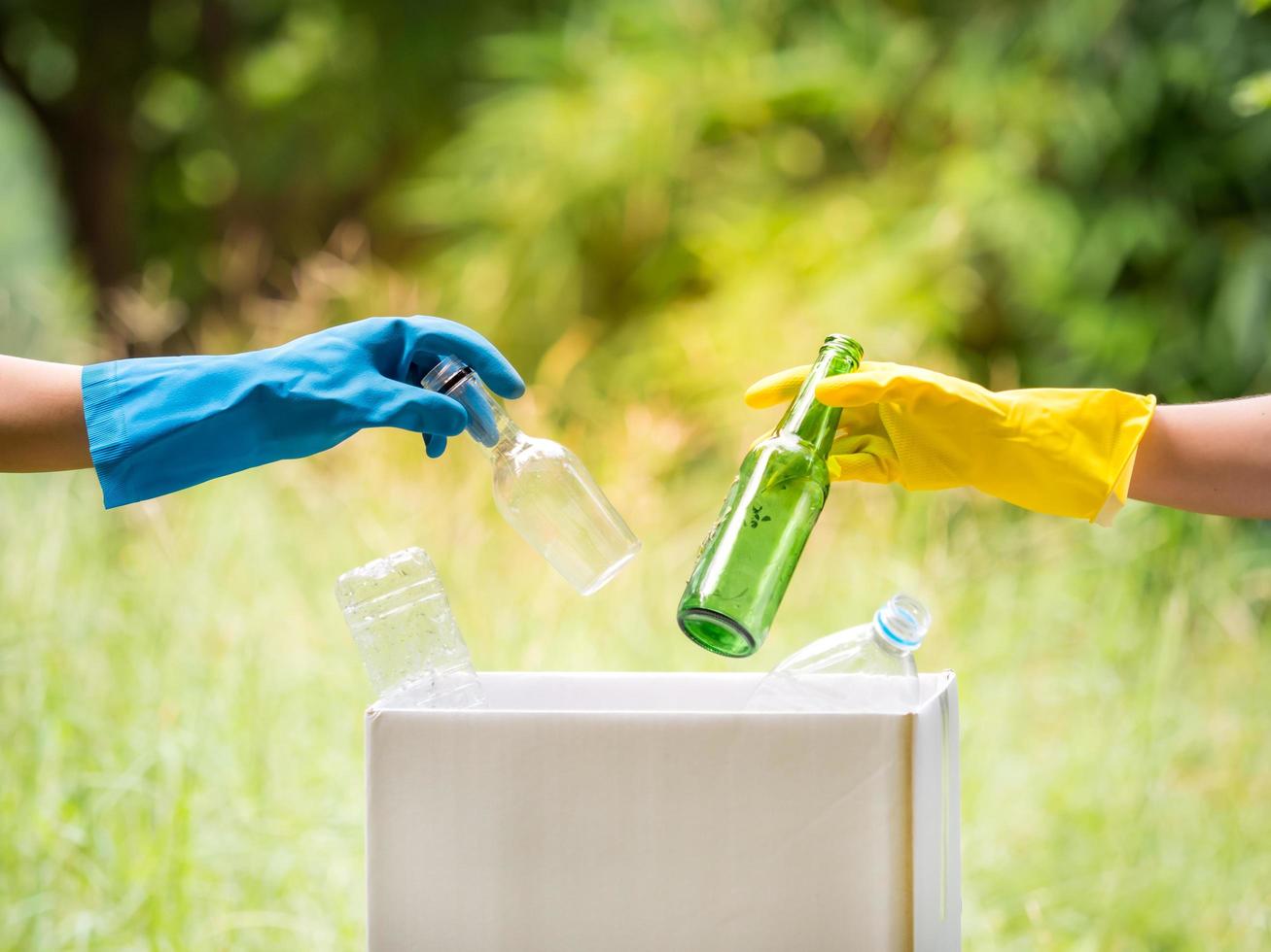 los voluntarios recogen botellas de agua de plástico en el área del parque, de personas que se niegan a tirar la basura en una caja de papel para reciclar foto