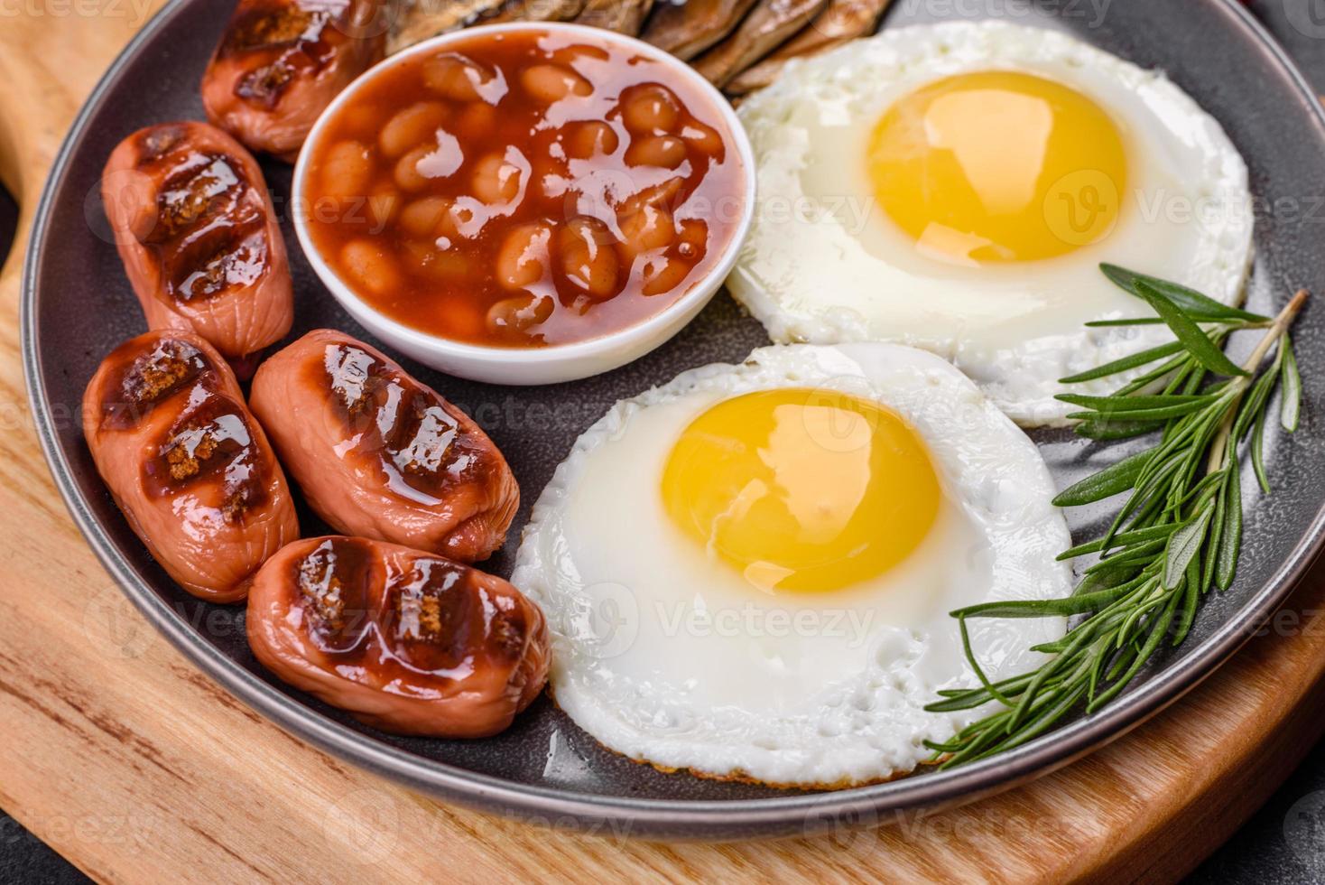 desayuno inglés completo con frijoles, huevos fritos, salchichas asadas, tomates y champiñones foto