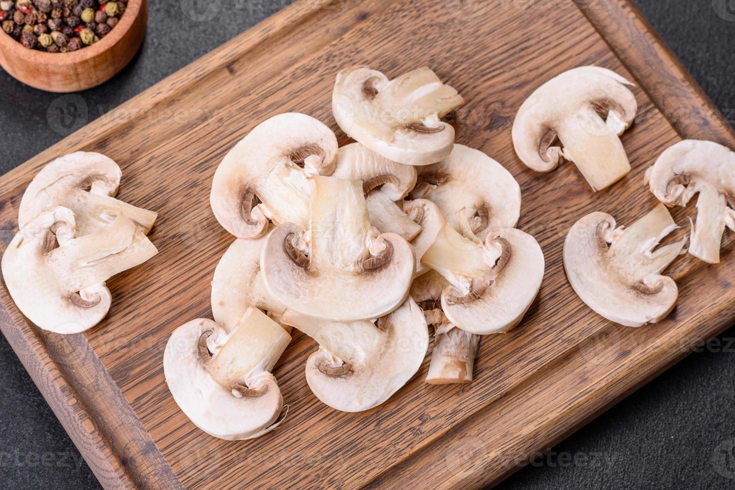 Beautiful young white champignons torn to slices on a dark concrete background photo