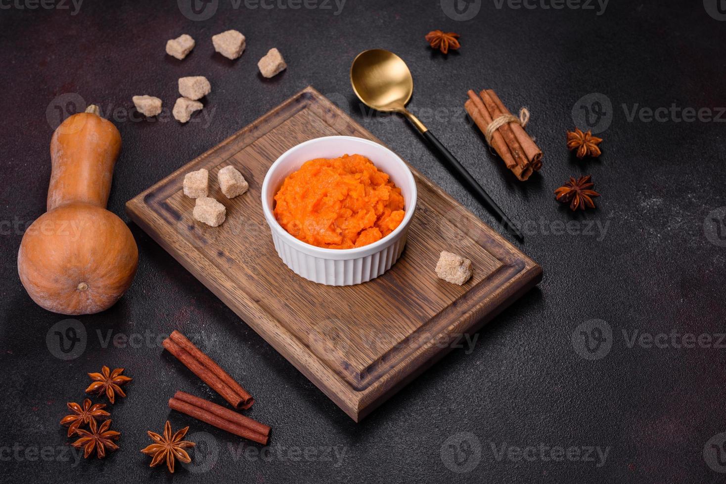 Pumpkin carrot baby puree in bowl on a dark background photo