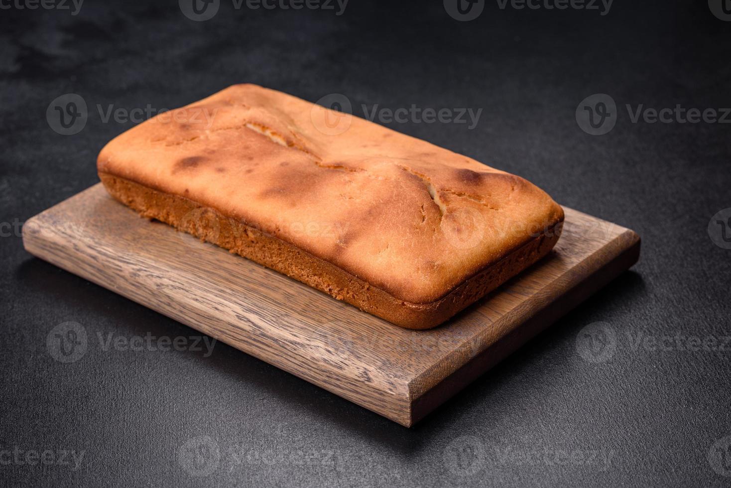 Baked rectangular cupcake with raisins and chocolate on a dark concrete background photo