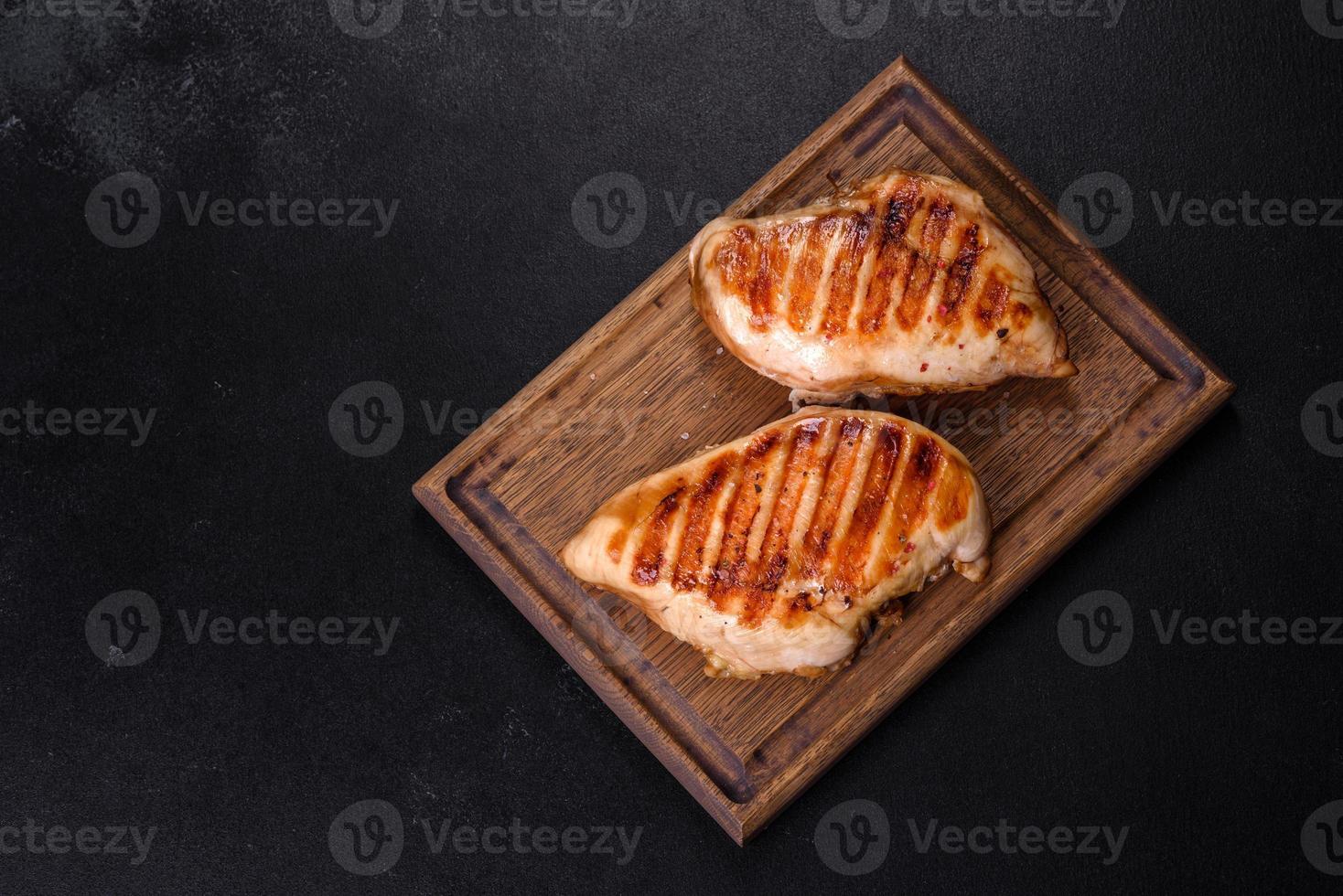 delicioso filete de pollo fresco a la parrilla con especias y hierbas sobre un fondo de hormigón oscuro foto