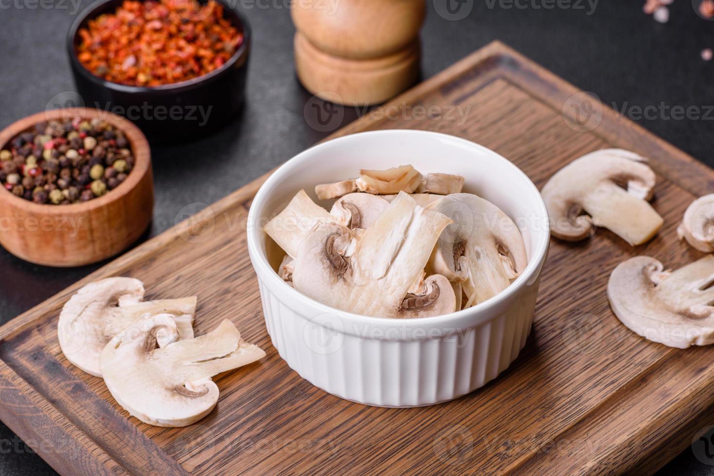 Beautiful young white champignons torn to slices on a dark concrete background photo