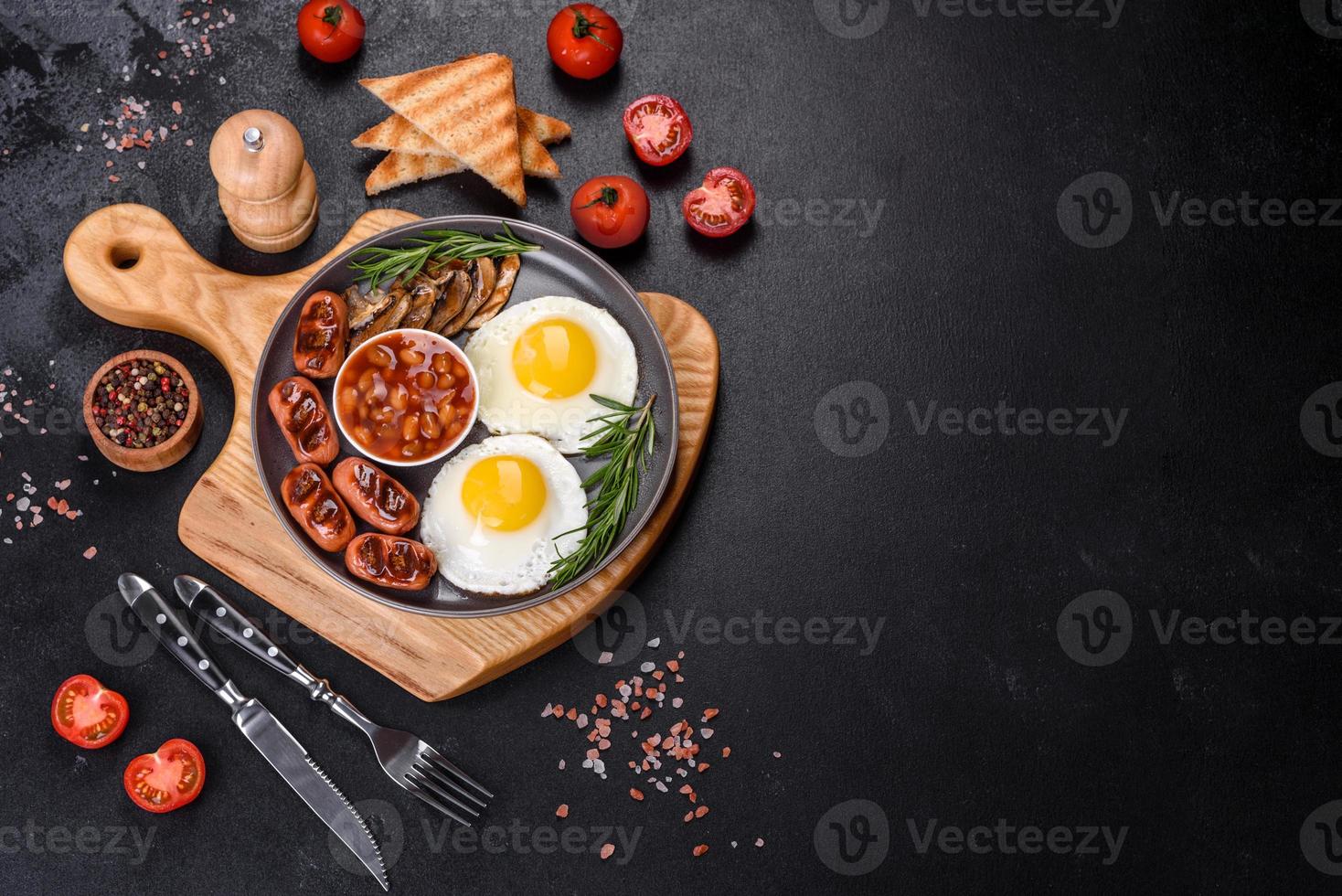 Full english breakfast with bean, fried eggs, roasted sausages, tomatoes and mushrooms photo