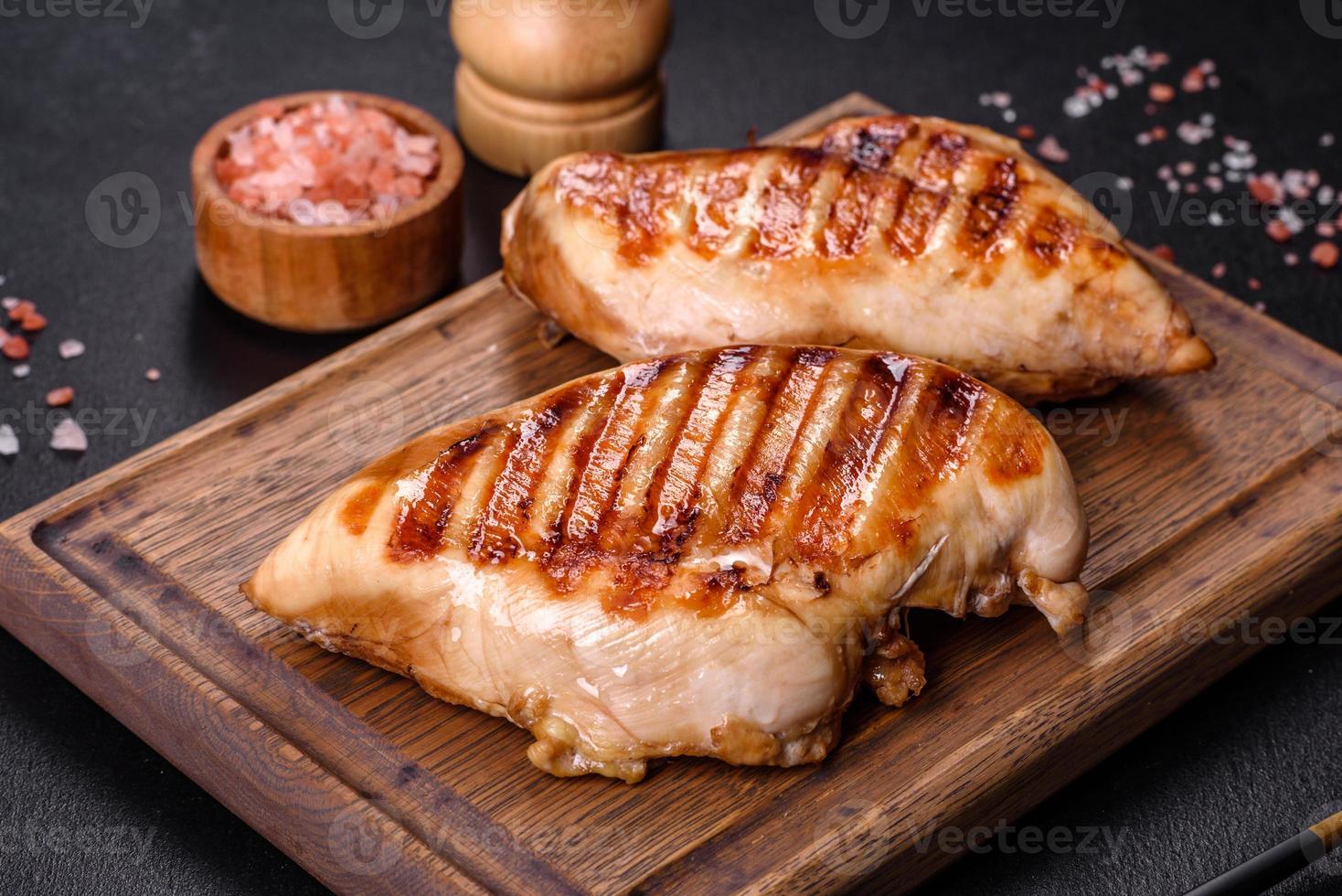 Delicious fresh grilled chicken fillet with spices and herbs on a dark concrete background photo