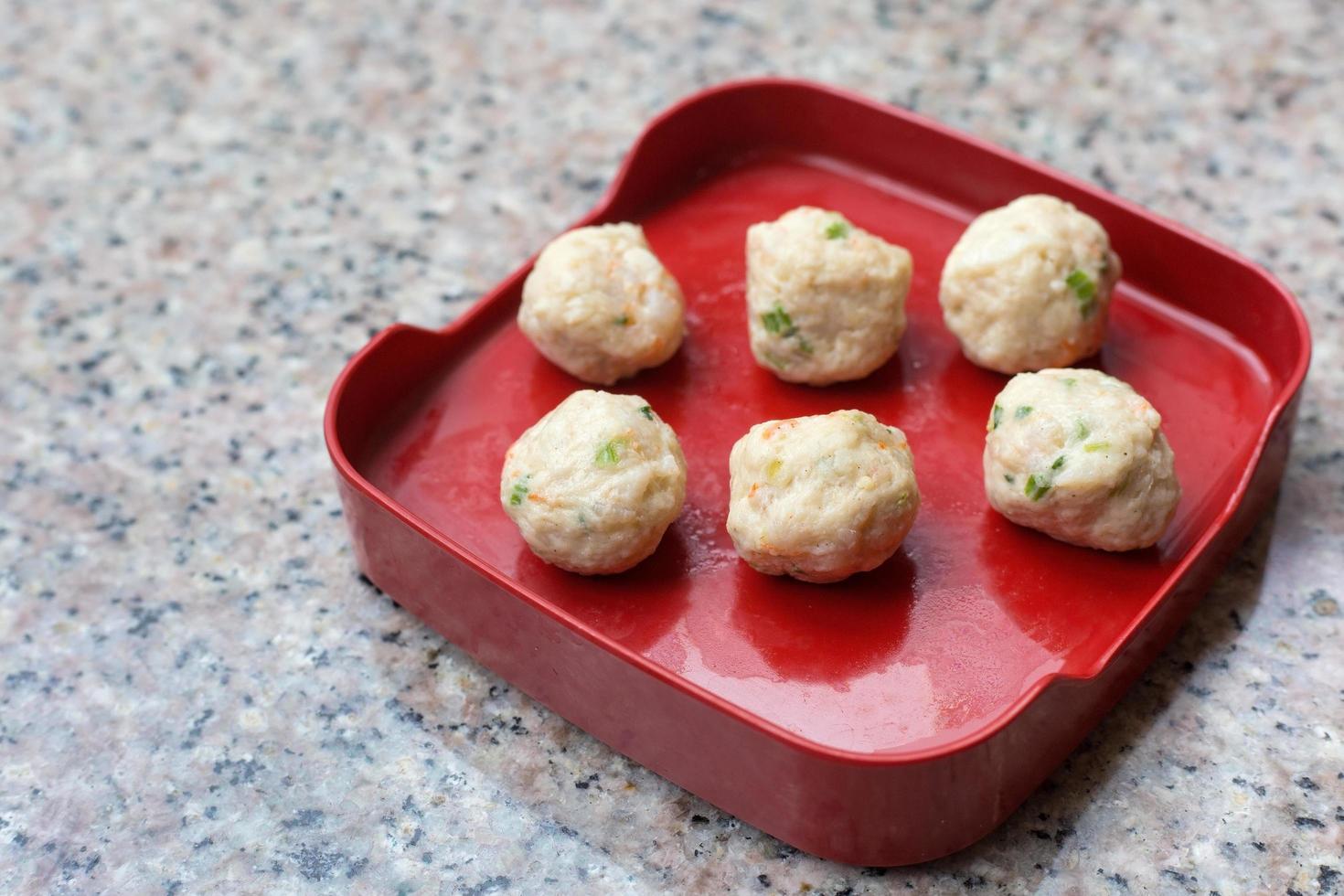 Meatballs are contained meat, flavoring and chopped vegetable which served on a red plate in Shabu or Sukiyaki restaurant. photo