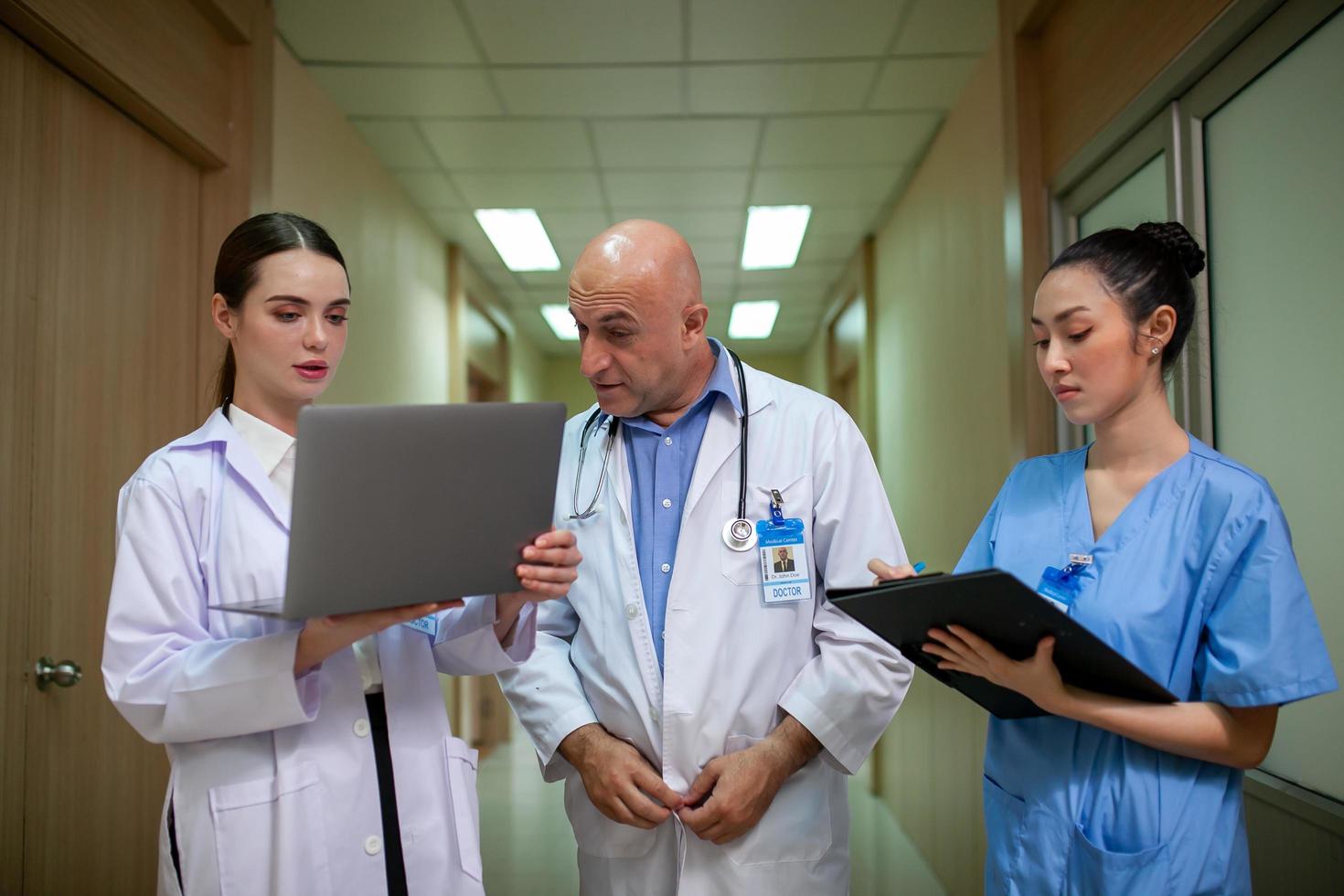 grupo de médicos que consultan los registros de los pacientes, un médico anciano y un colega que discuten la terapia actual de enfermedades en el lugar de trabajo. foto