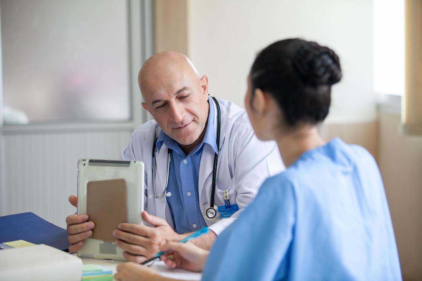 grupo de médicos que consultan los registros de los pacientes, un médico anciano y un colega que discuten la terapia actual de enfermedades en el lugar de trabajo. foto