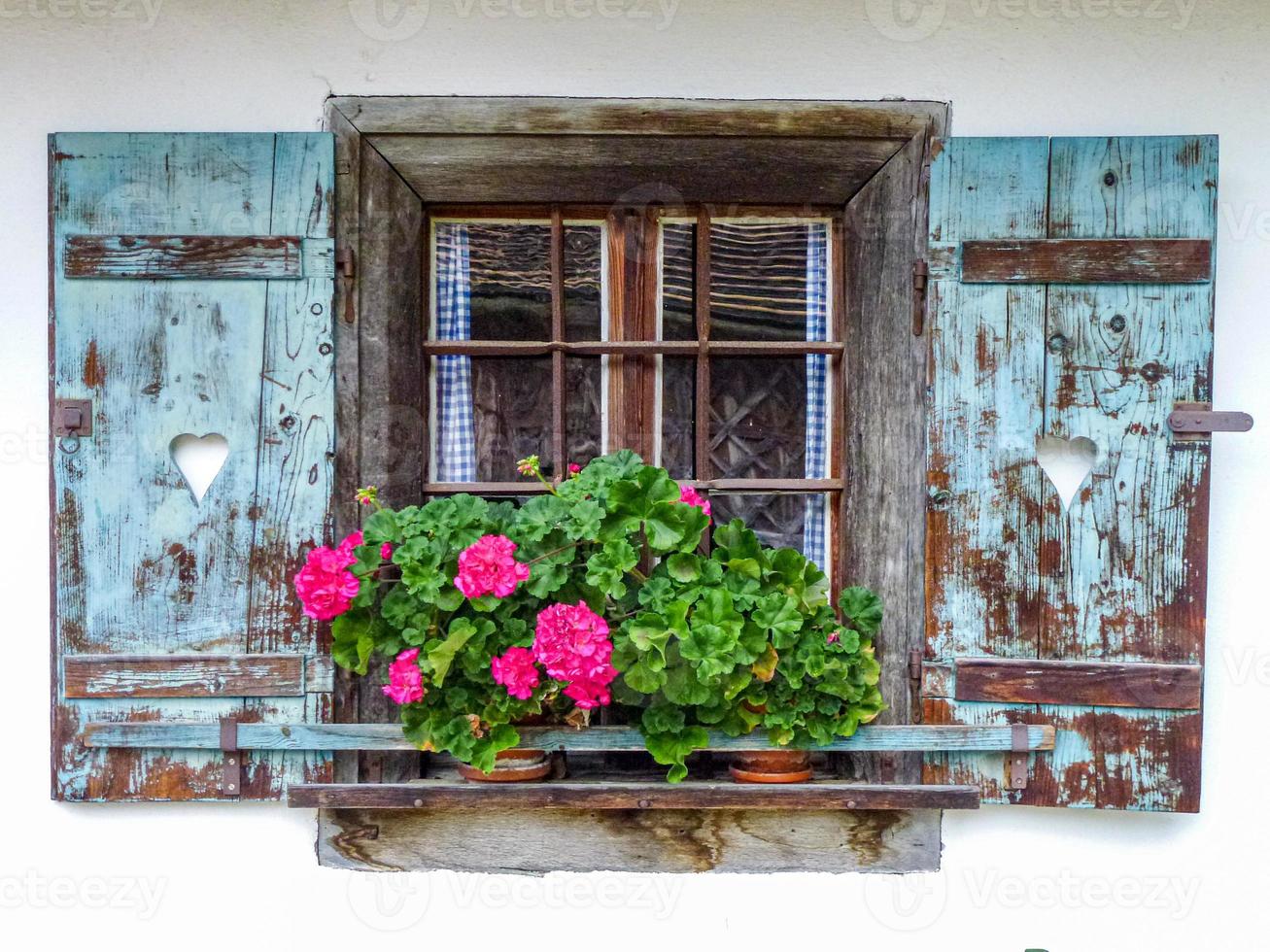 primer plano de una vieja ventana de madera con flores en el alféizar foto