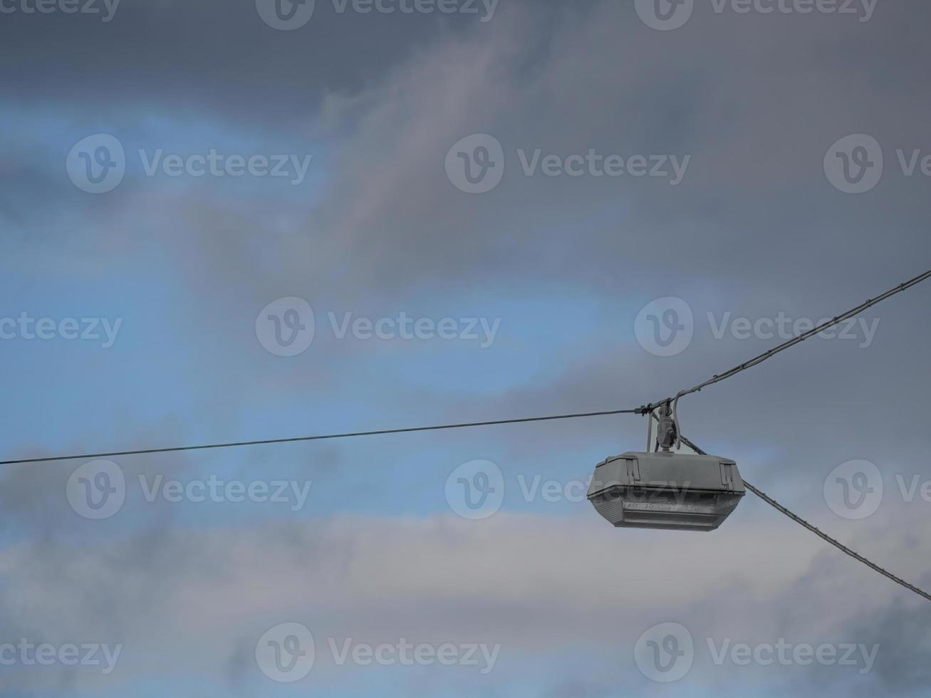 Low angle shot of a hanging light on cables against a cloudy sky background photo