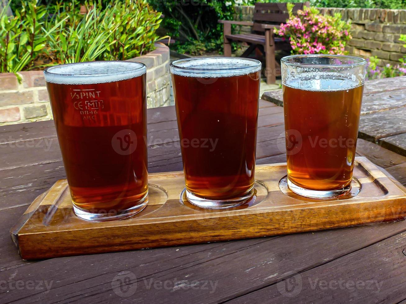 primer plano de tres vasos de cerveza fría fresca en una mesa de madera en un restaurante foto