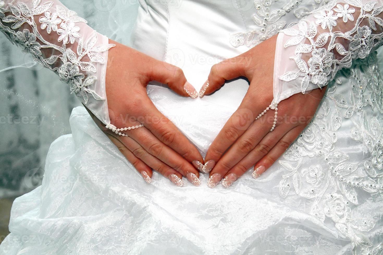 hands of fiancee on a dress as a heart photo