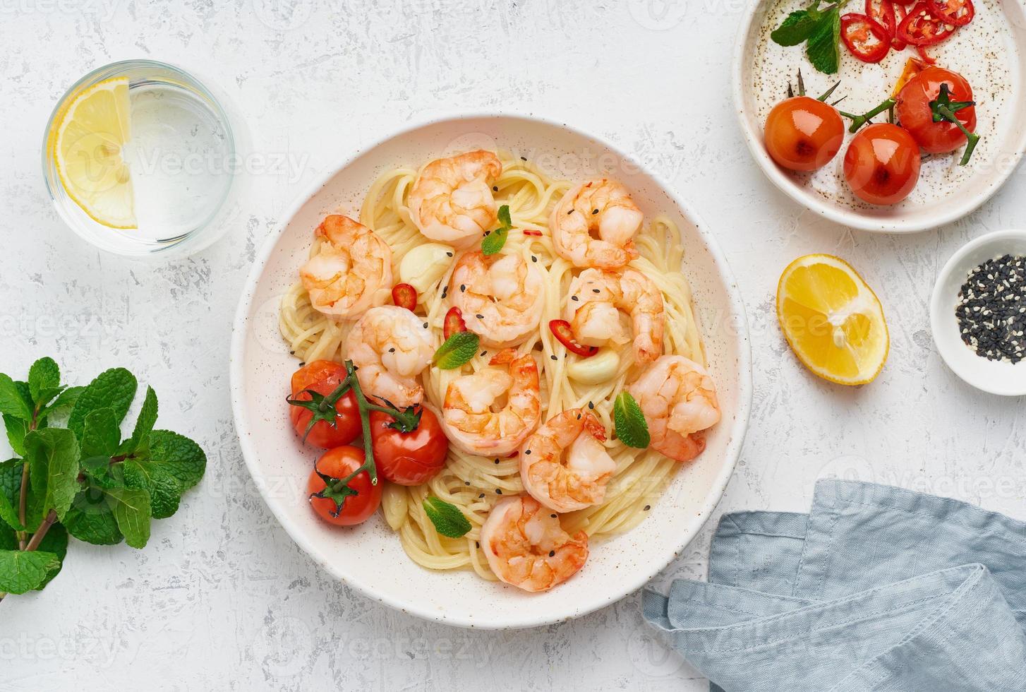 Pasta bavette with fried shrimps, bechamel sauce, mint leaf, garlic, on white plate, top view photo