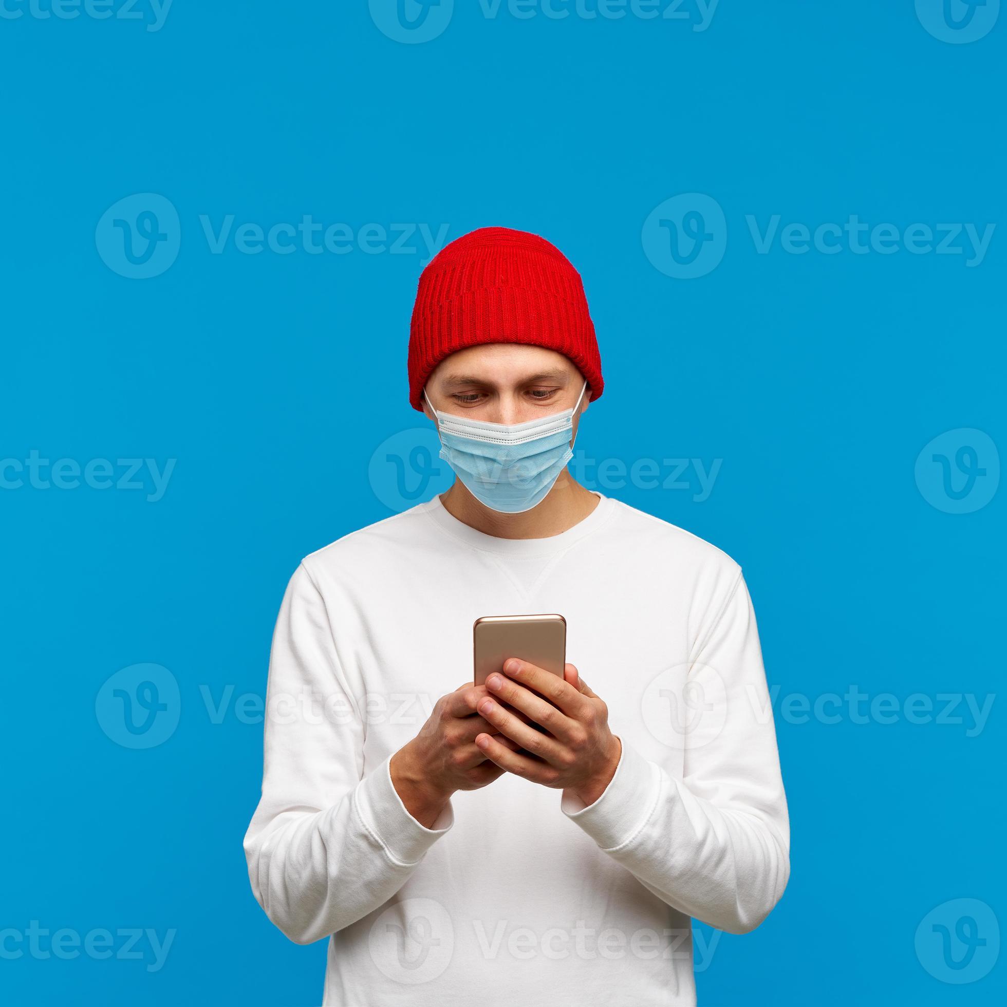 Portrait of man with medical protective face mask, texting on mobile